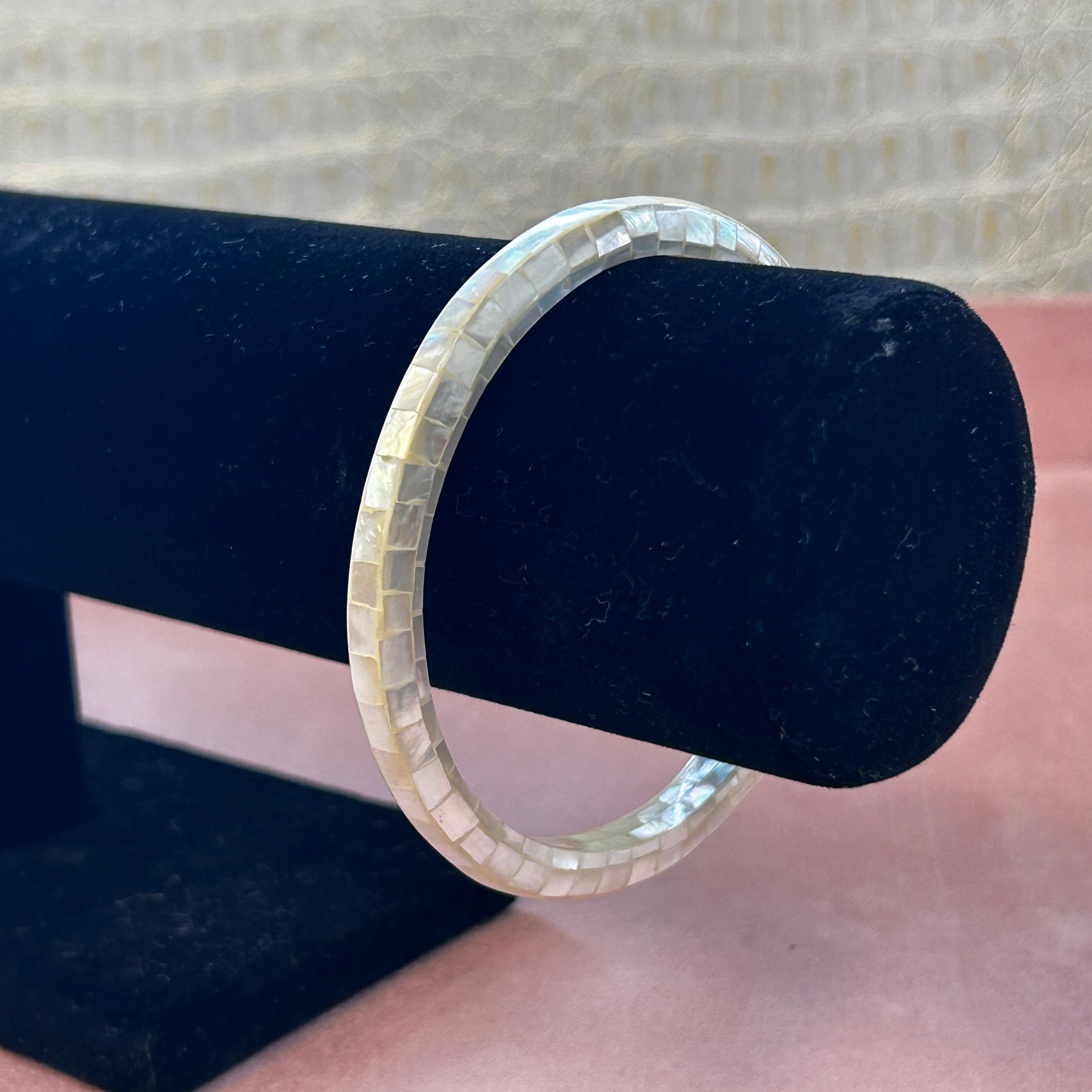 Silver ring on a black jewelry stand with a blurred background